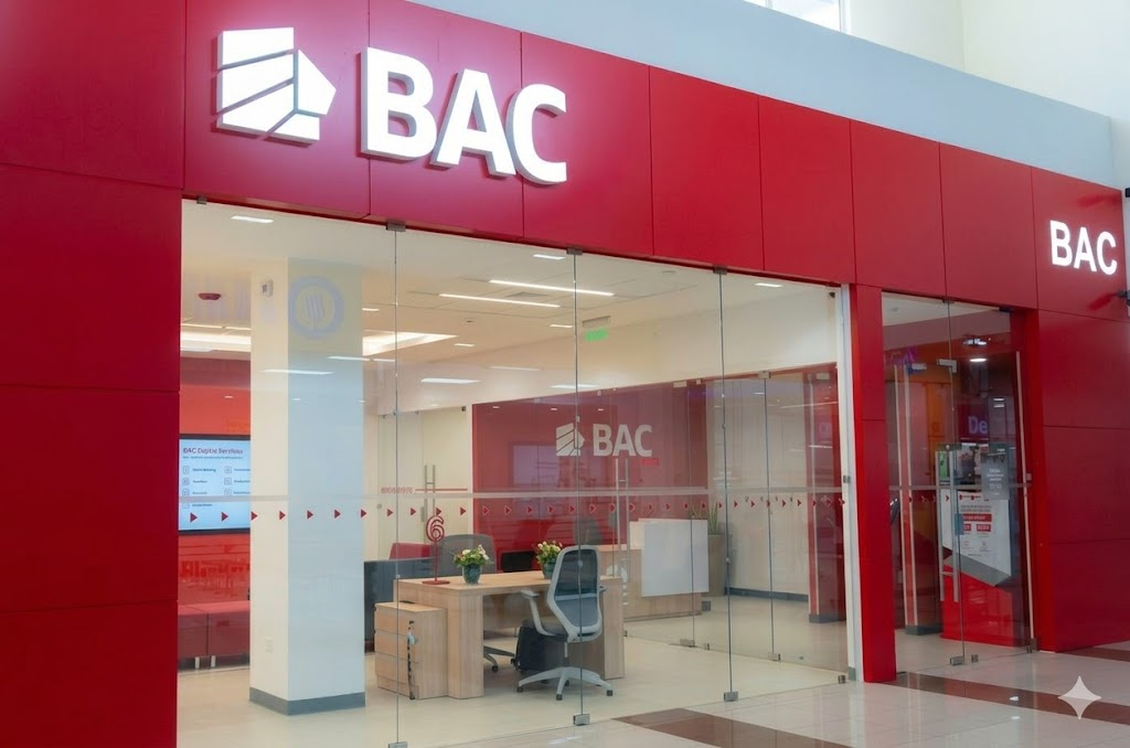 "Interior de una sucursal moderna de BAC Credomatic en Panamá, con señalética roja, escritorios de madera y estaciones de servicios digitales."