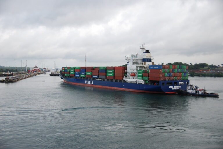 Un buque portacontenedores de la naviera Italia navegando por el Canal de Panamá con la asistencia de un remolcador.