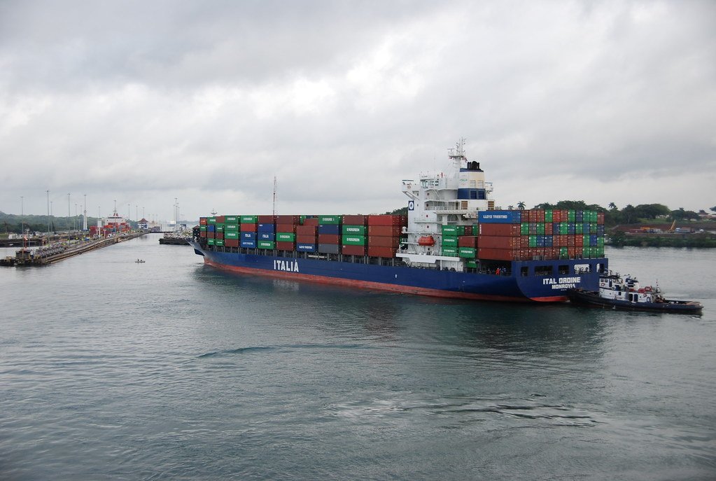 Un buque portacontenedores de la naviera Italia navegando por el Canal de Panamá con la asistencia de un remolcador.