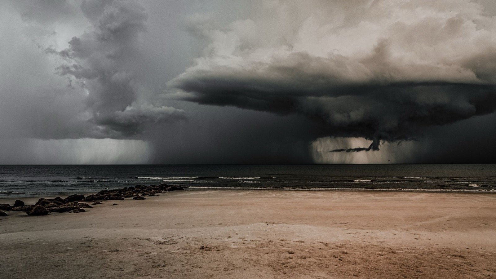 Nubes oscuras de tormenta sobre una playa y el océano