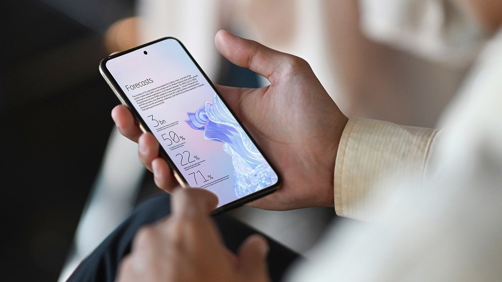 Una persona sostiene un teléfono con las previsiones del Ericsson Mobility Report 2026