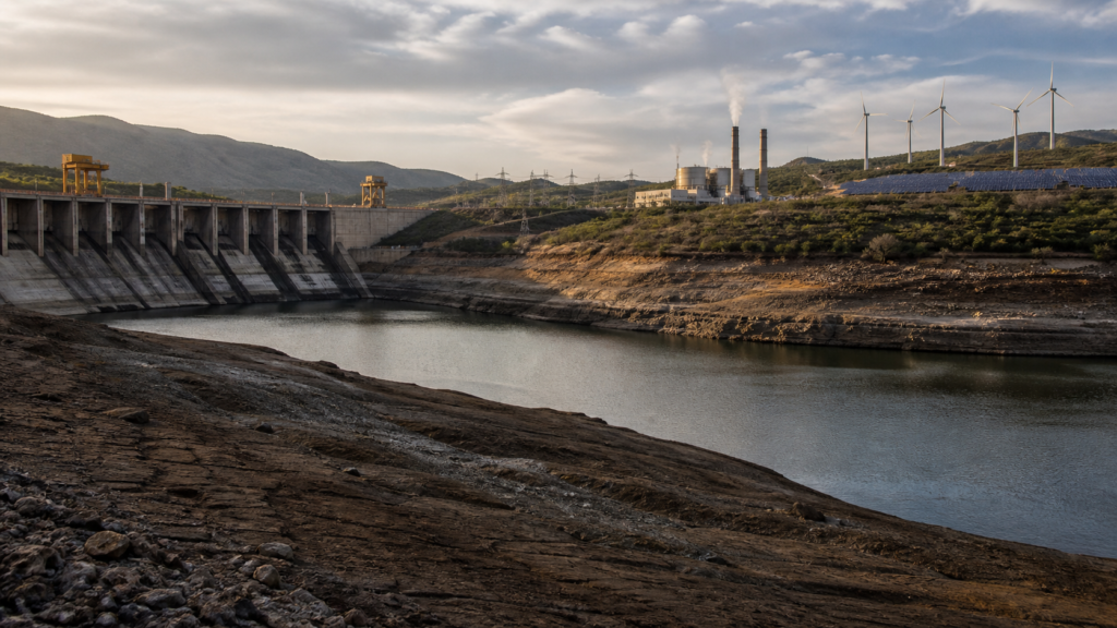 Embalse hidroeléctrico con bajo nivel de agua, planta térmica, turbinas eólicas y paneles solares