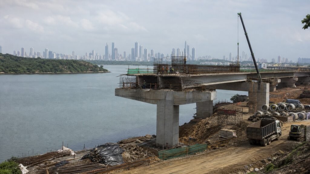 Construcción de un puente sobre una vía acuática con la ciudad de Panamá al fondo