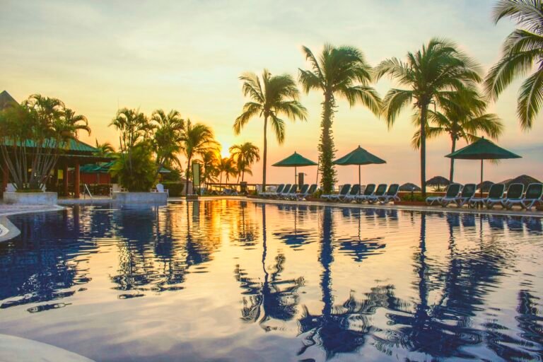 Piscina rodeada de palmeras durante el atardecer en Farallón, Panamá