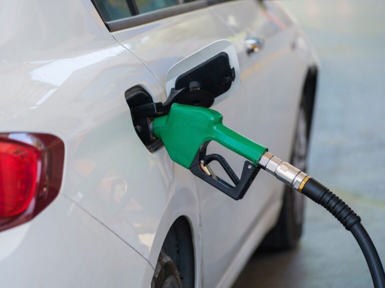 Boquilla de combustible verde conectada al tanque de un automóvil blanco