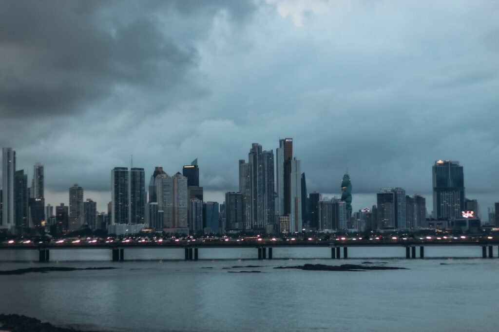 Edificios de la ciudad de Panamá al atardecer, con una vía iluminada sobre el agua en primer plano.