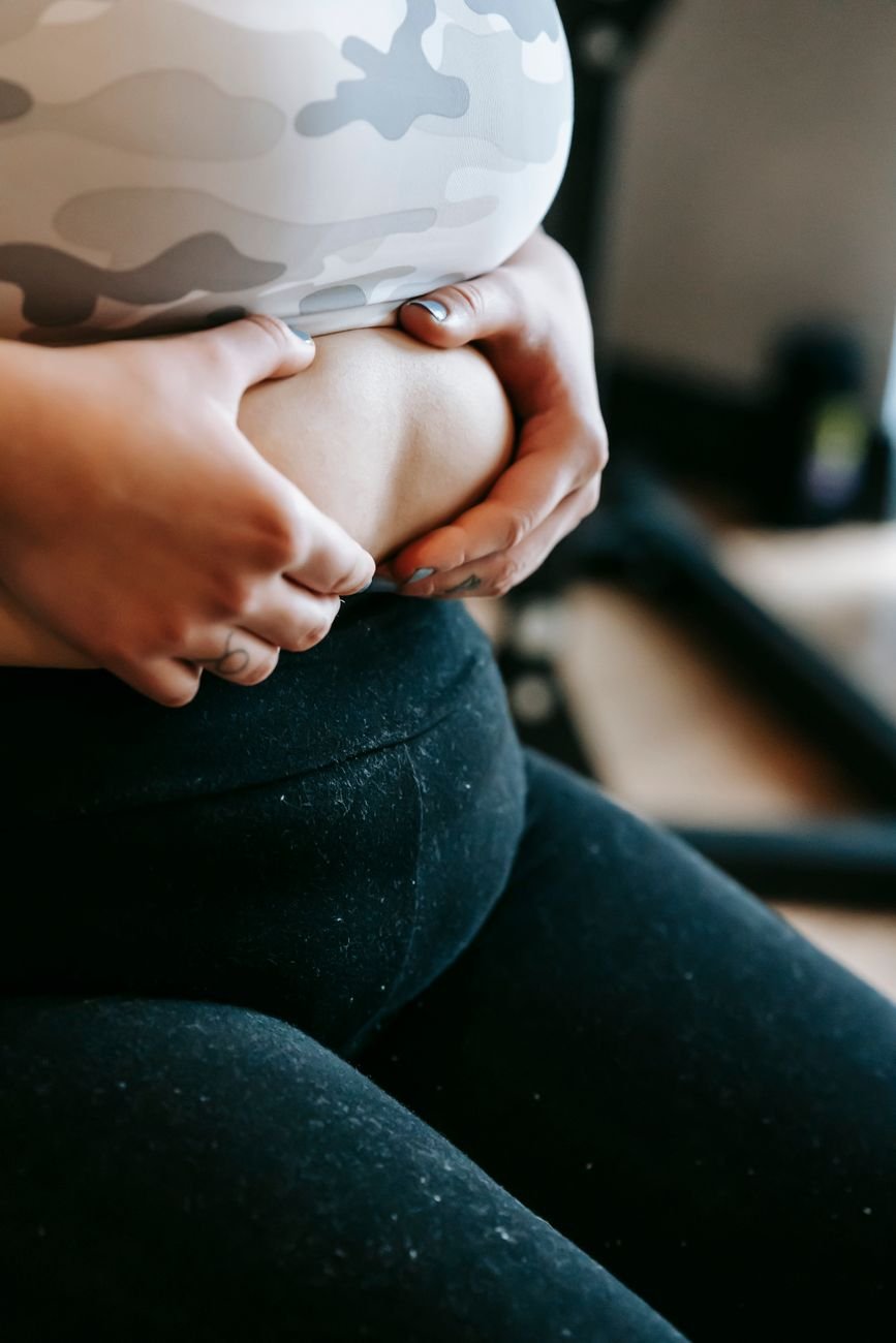 unrecognizable plus size lady touching stomach in gym