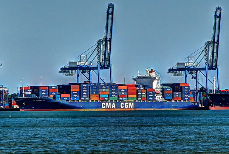 Un buque portacontenedores de la naviera CMA CGM siendo cargado por grúas pórtico en una terminal portuaria.