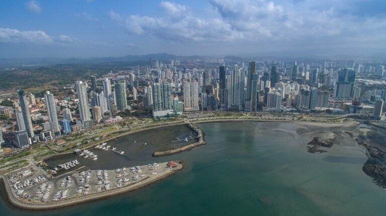Vista aérea del distrito financiero de la Ciudad de Panamá con rascacielos frente a la costa y un puerto deportivo en primer plano.