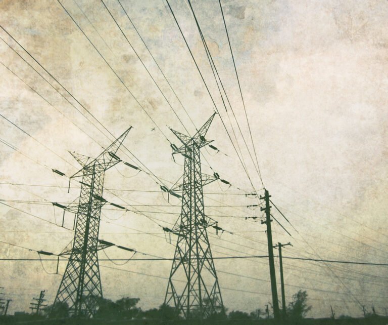 Dos torres de alta tensión de metal con cables eléctricos extendidos bajo un cielo nublado.