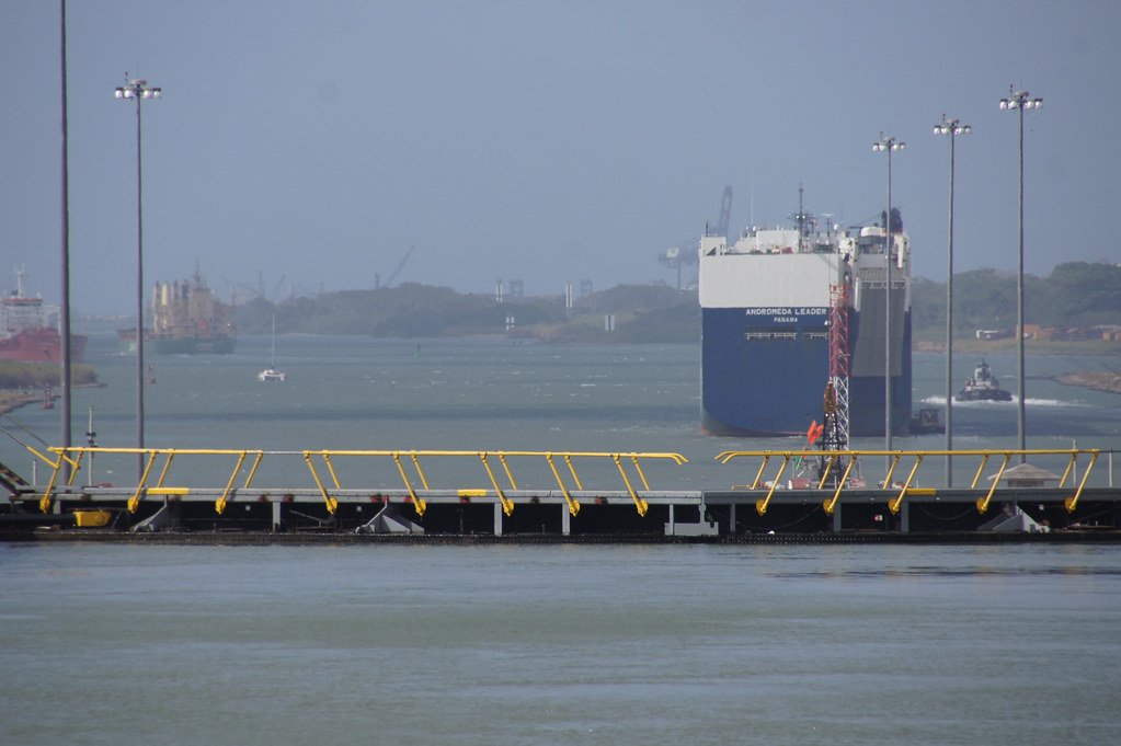Un gran barco de carga navegando por el Canal de Panamá con una estructura de compuerta o puente móvil en primer plano.