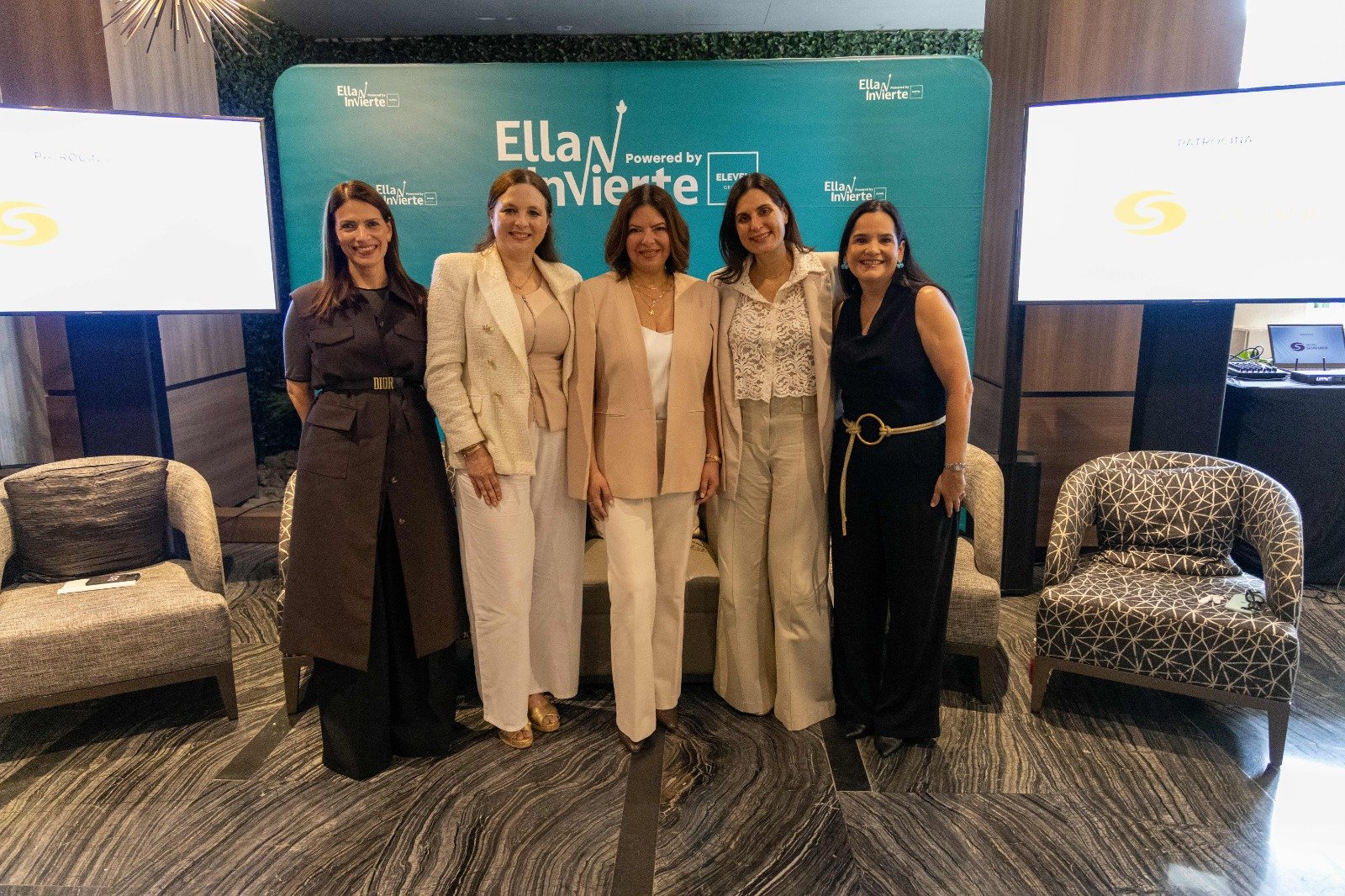 Cinco mujeres posan ante el mural del Ella Invierte Summit 2026