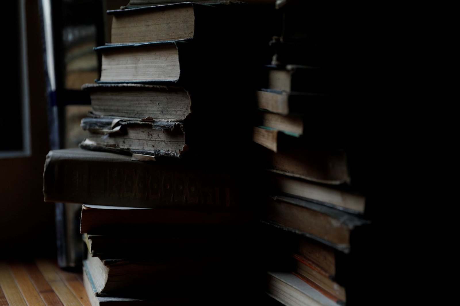 Pilas de libros antiguos en una habitación con poca luz