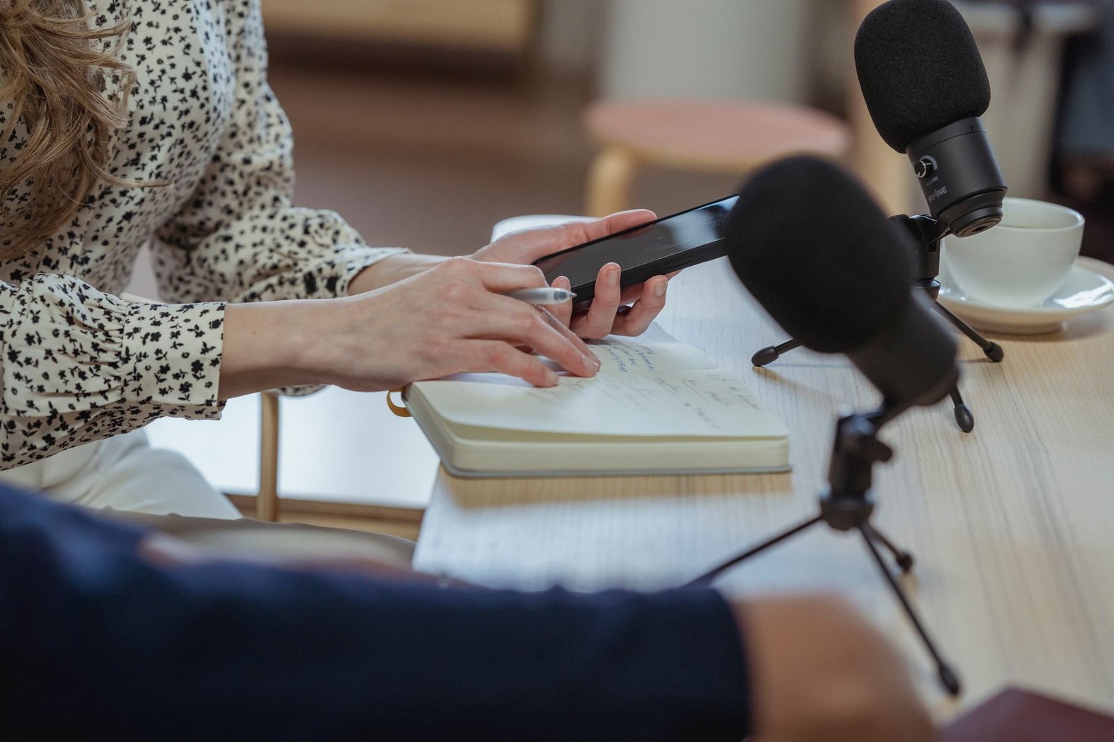 woman using smartphone and taking notes in notebook