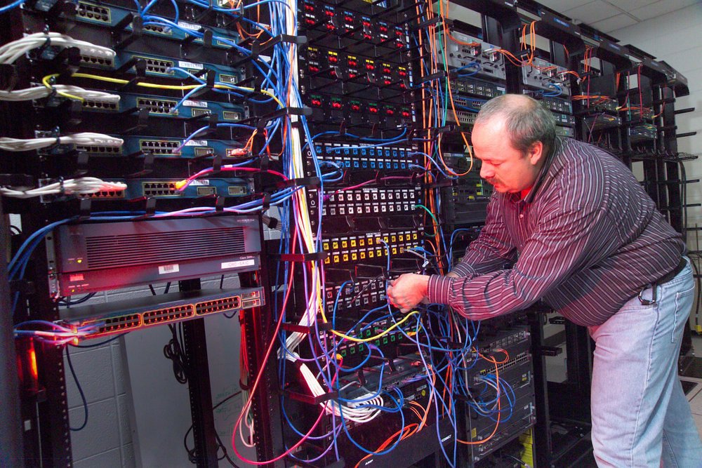 Un técnico trabajando en la gestión de cables y conexiones de servidores en un centro de datos.